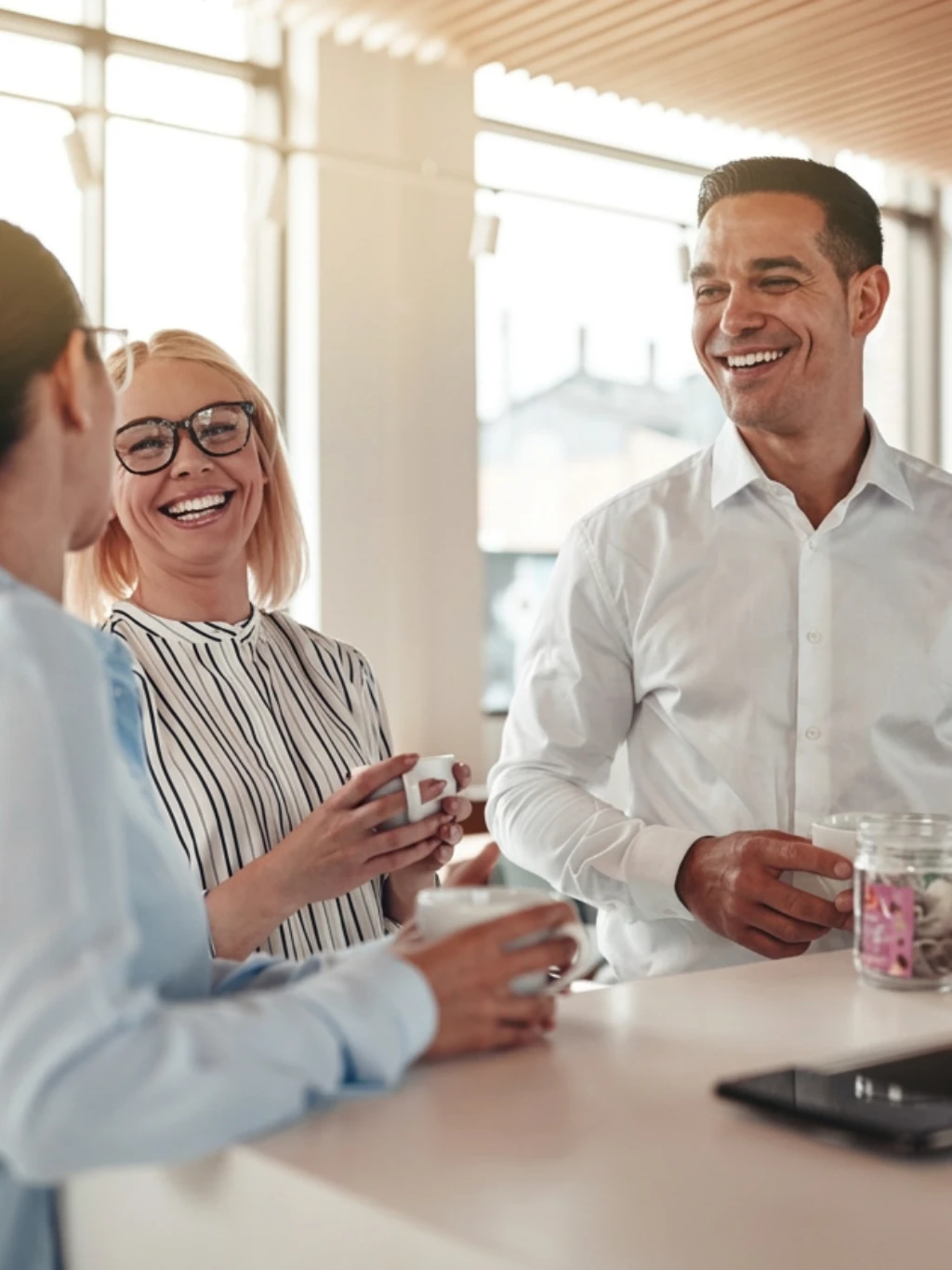 Three people in the office chatting over coffee