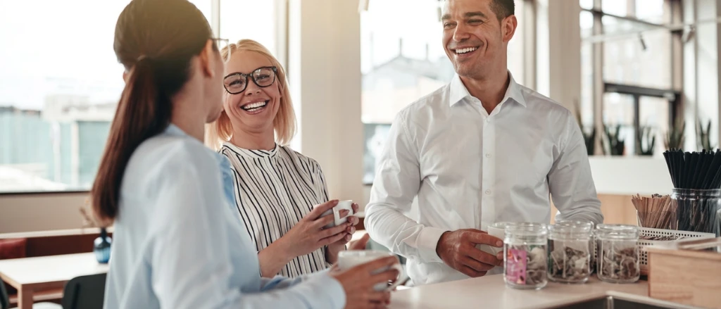 Three people in the office chatting over coffee