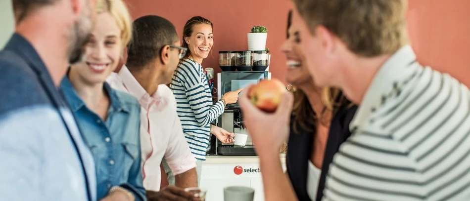 A group of people enjoying office coffee made with a tabletop coffee machine